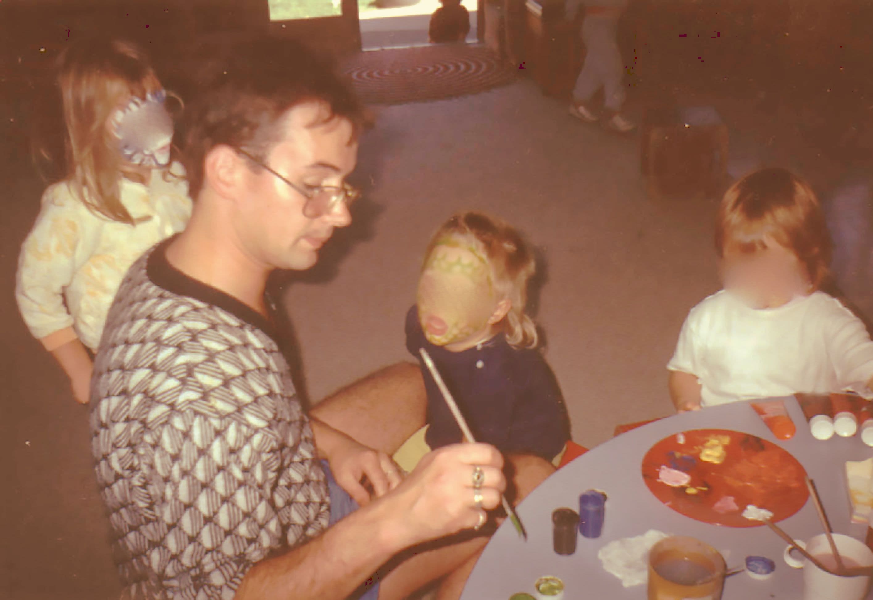 Peter Ellis painting faces at the Christchurch Civic Creche. The children's faces have been blurred.
